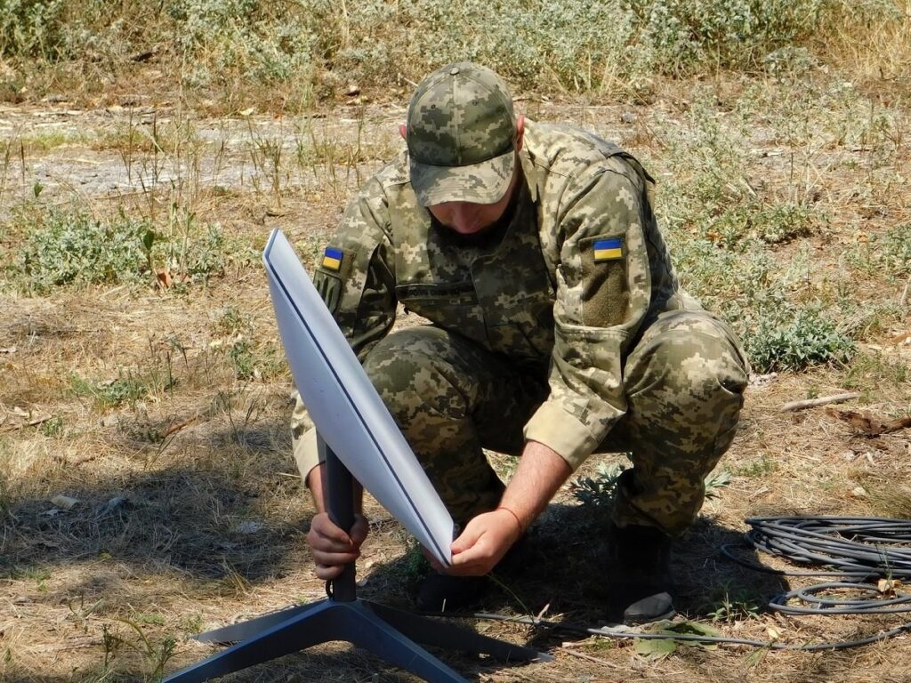 Militar ucrainean instalând un terminal Starlink pe teren, fotografie de arhivă din 2022