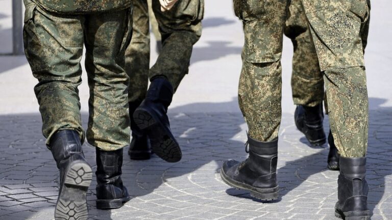 Soldați în uniforme de camuflaj mergând, fotografiați de la brâu în jos