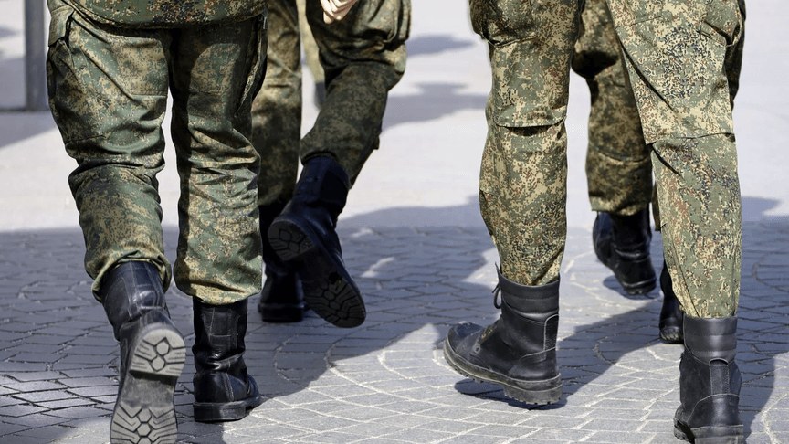 Soldați în uniforme de camuflaj mergând, fotografiați de la brâu în jos